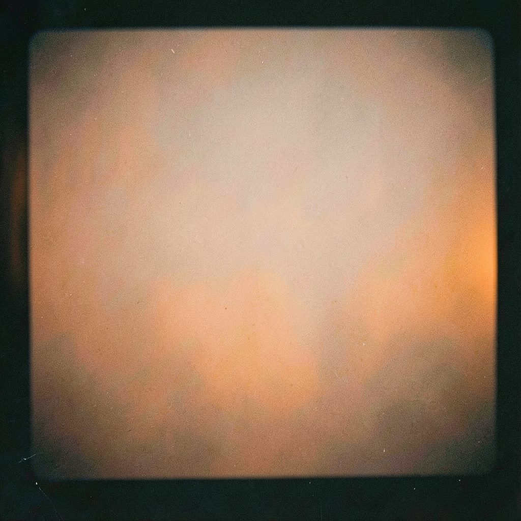 Grainy analog film photograph of a small video camera and film reel, dim green-toned lighting, documentary mood